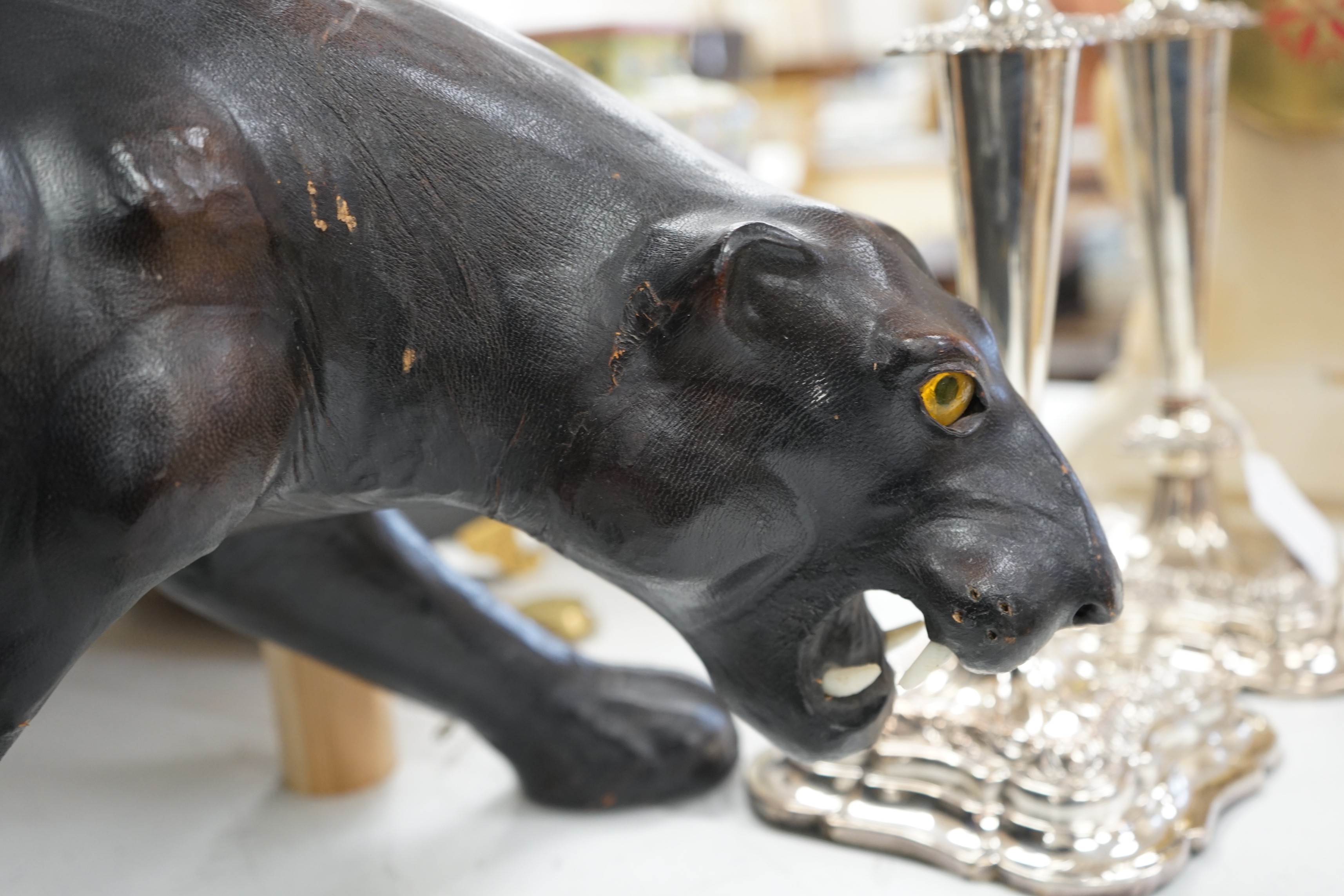 A Liberty’s-style black leather panther footstool, 75cm wide